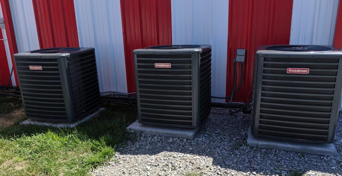 Three commercial condensing units installed against a building wall